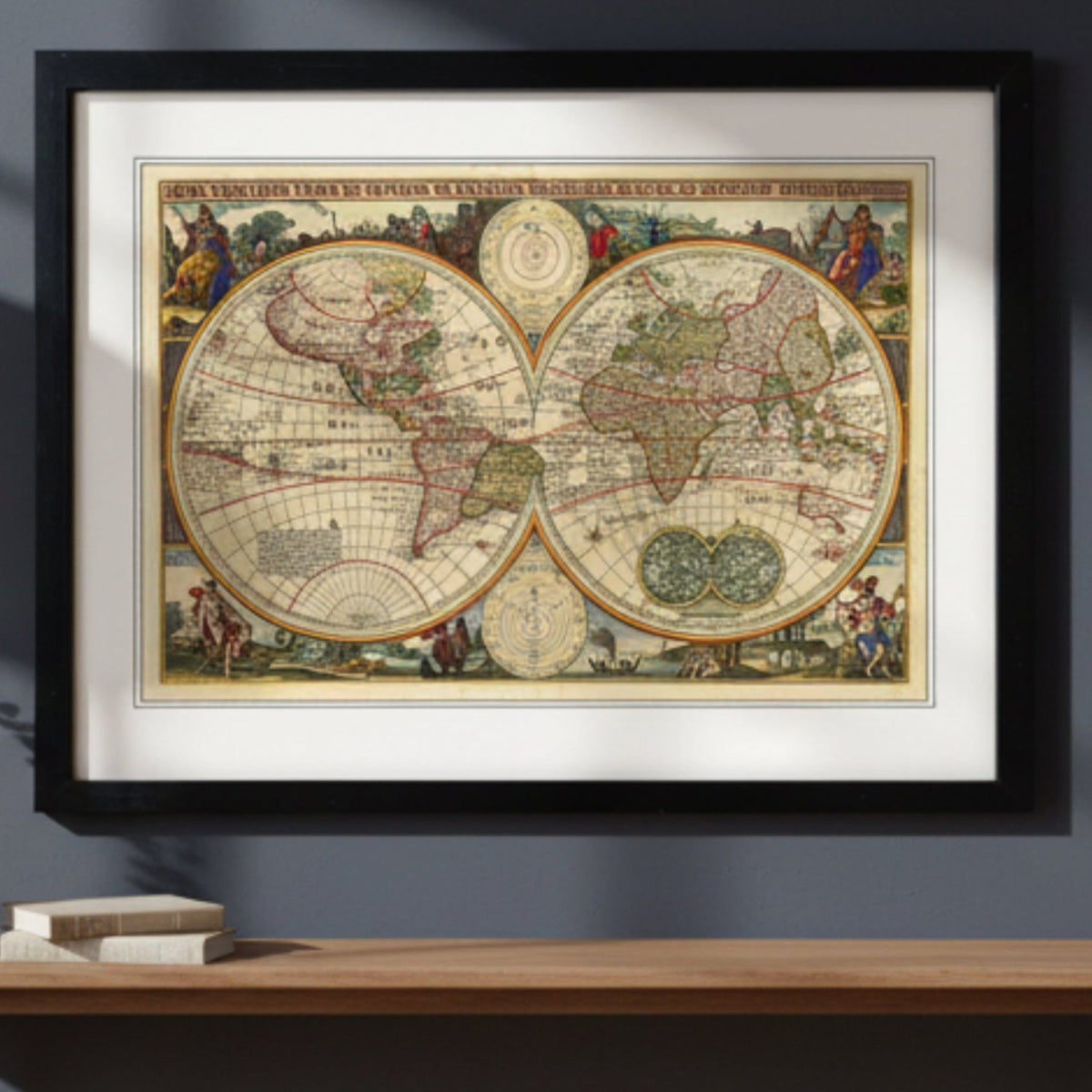 A framed vintage world map print with two large hemispheric globes, an ornate cream border, and small decorative figures around the map. The print is shown in a black frame with a white mat against a plain white background.