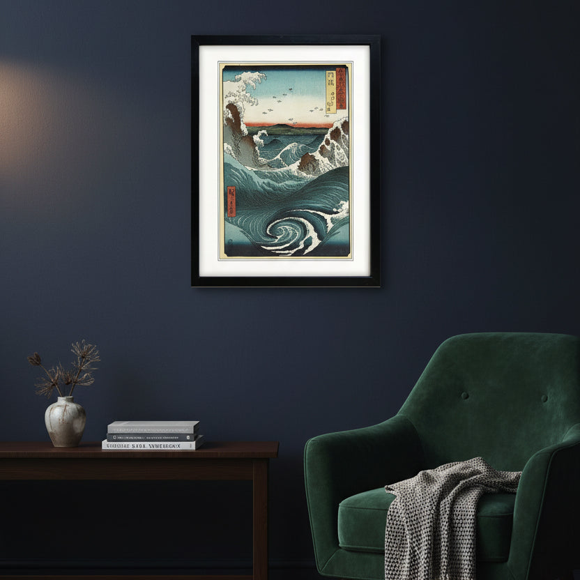 A framed Japanese-style wave artwork hanging on a white wall. The print shows large blue and white ocean waves, dark rocky shorelines, a pale sky, and small red vertical label panels with Japanese text.