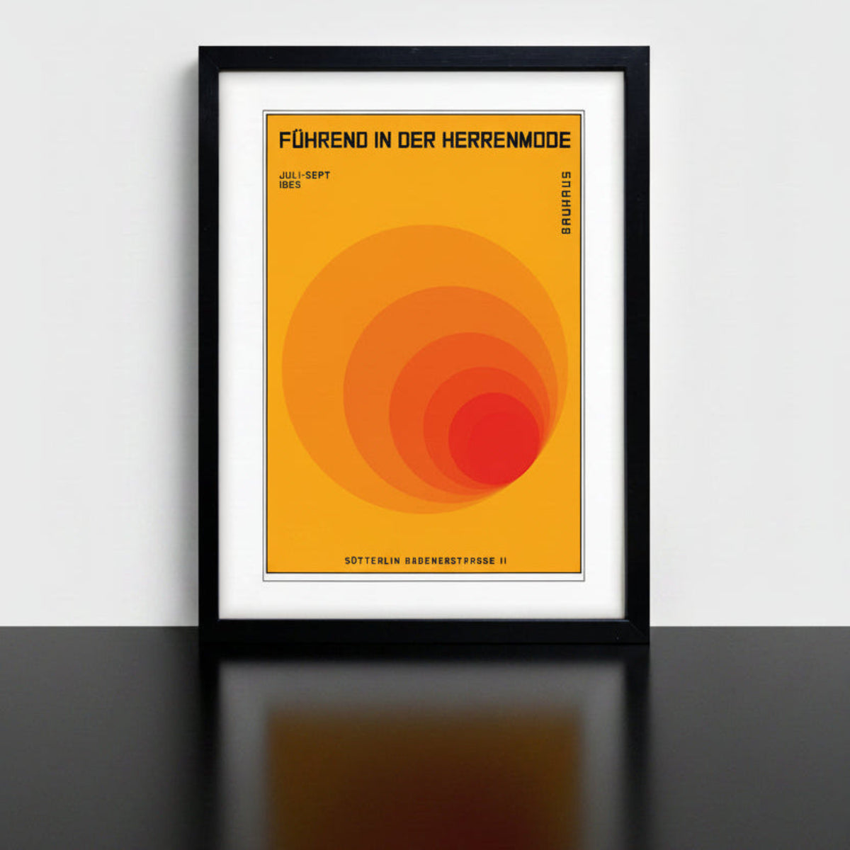 A framed Bauhaus poster print featuring a retro-style orange and red concentric circle design with German text, shown in a black frame against a white background.