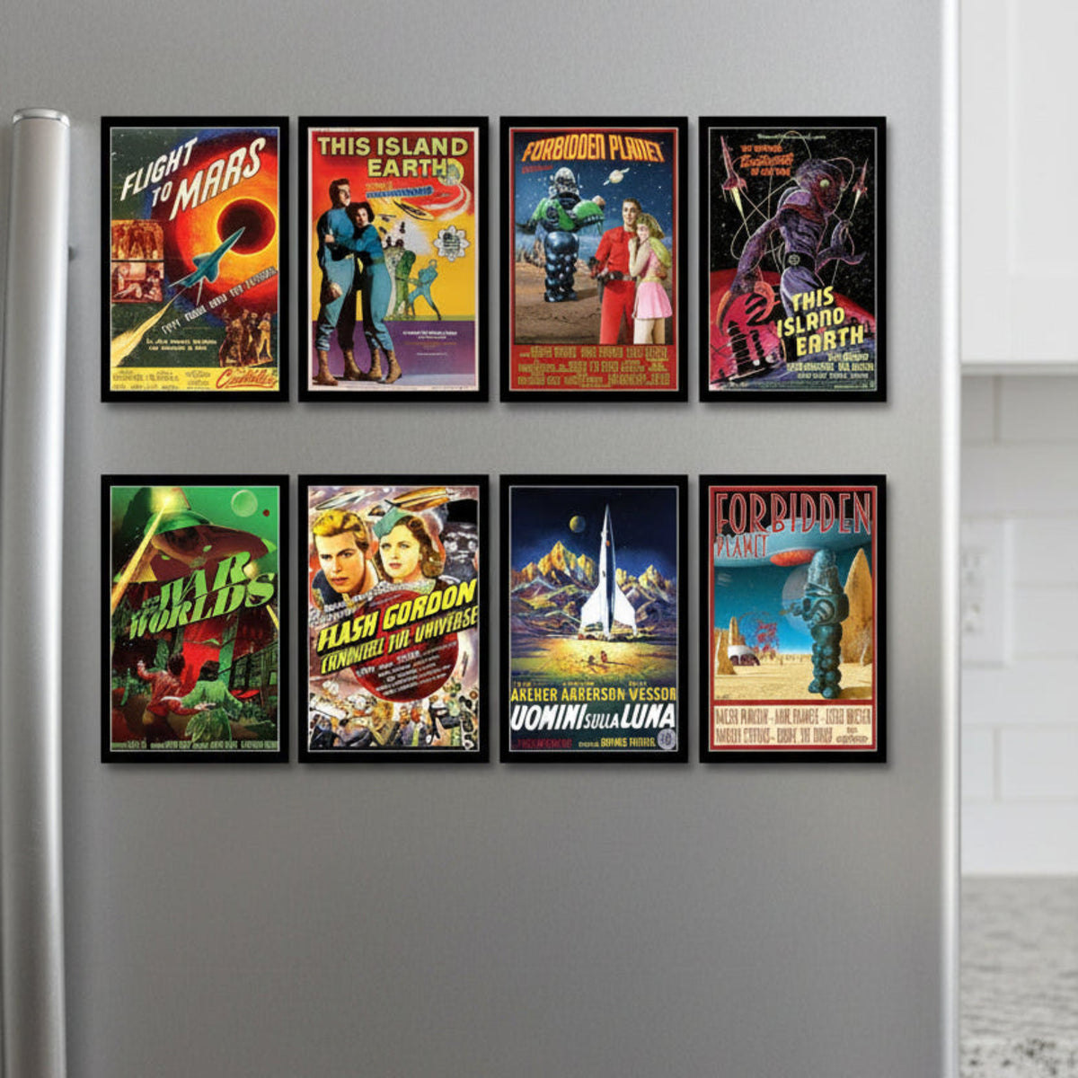 Eight framed vintage science fiction movie posters arranged in two rows on a gray wall. The fridge magnets feature classic pulp artwork including titles such as Flight to Mars, This Island Earth, Forbidden Planet, This Island Earth Part 2, Flash Gordon, Uomini Equilqua, and Forbidden Land.