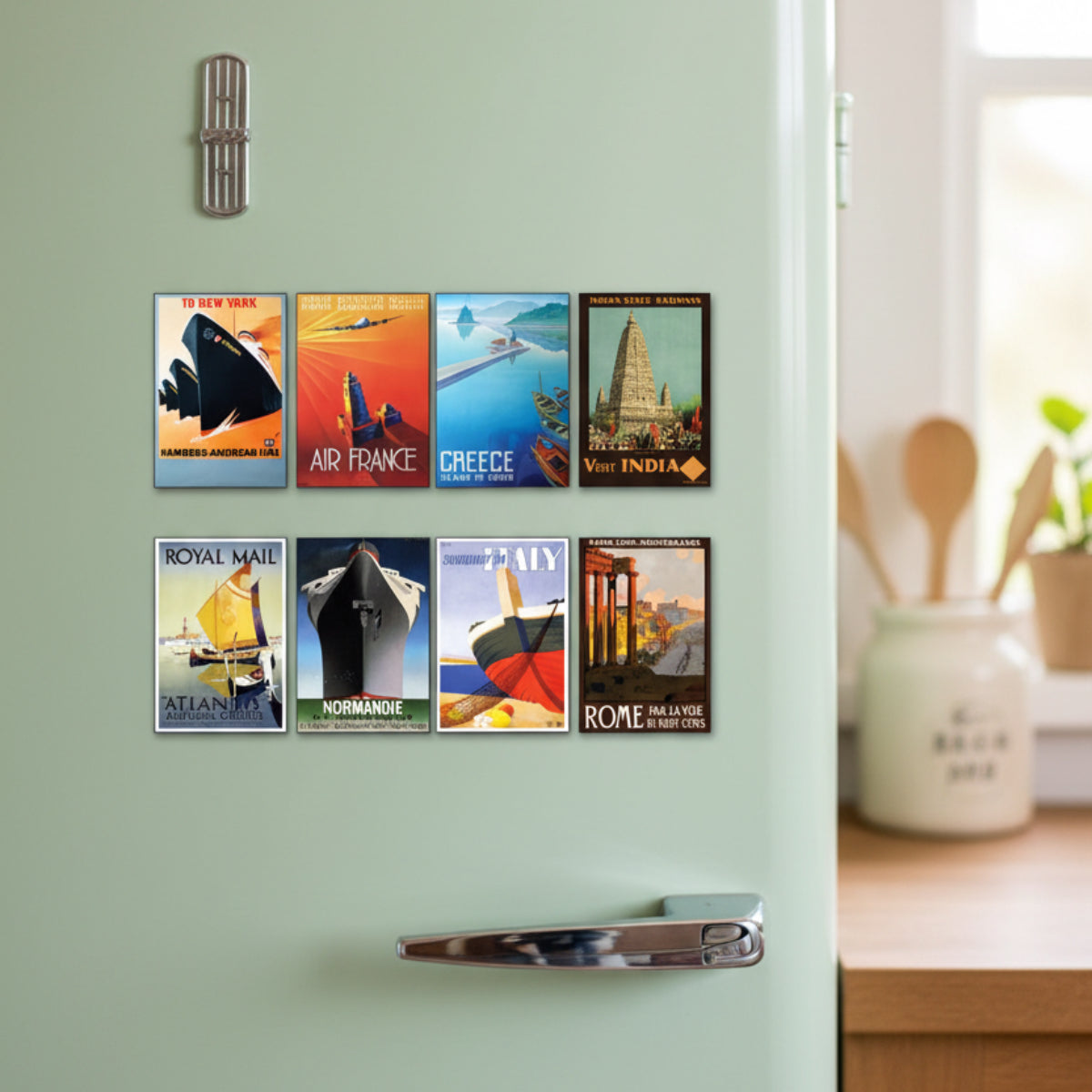 A set of eight vintage-style travel poster prints fridge magnets arranged in two rows on a light gray background. The posters feature illustrated scenes and typography for destinations and routes including New York, Air France, Greece, India, Atlantic cruises, Normandie, Italy, and Rome.