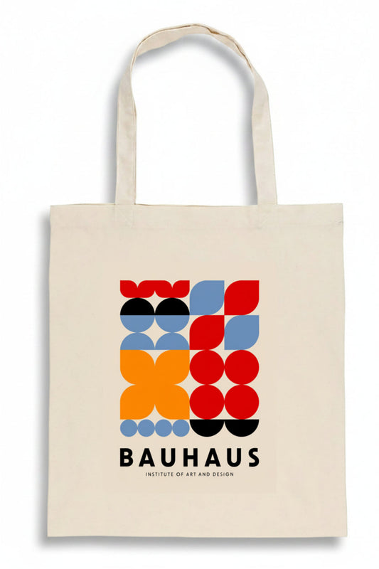 A cream-colored canvas tote bag featuring a colorful Bauhaus geometric logo print in red, orange, blue, black, and white, with the text 'BAUHAUS INSTITUTE OF ART AND DESIGN' printed below.