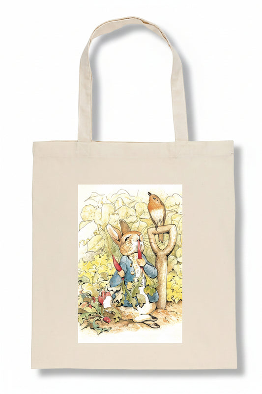 A beige canvas tote bag featuring a printed illustration of Beatrix Potter characters, including Peter Rabbit and a robin, on a white background.