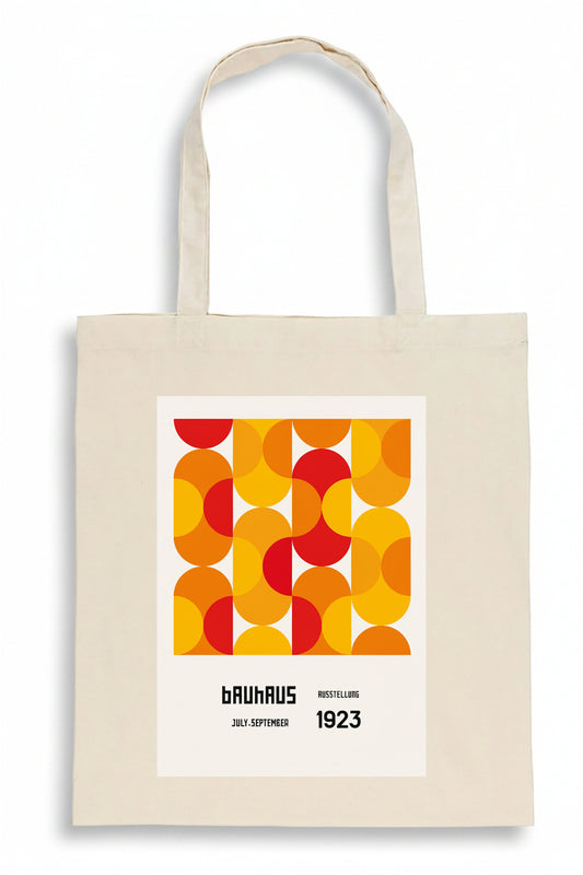 A cream-colored canvas tote bag featuring a retro graphic print with overlapping orange, yellow, and red circles, and text reading 'brauhaus', 'mottellus', '20 09 1923'.
