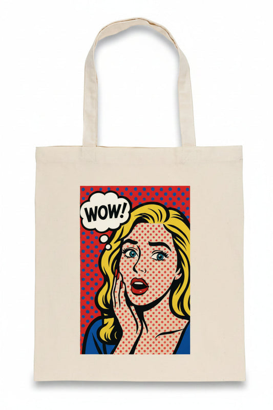 A cream-colored canvas tote bag featuring a pop-art graphic of a surprised blonde woman with a 'WOW!' speech bubble on a red polka-dot background.