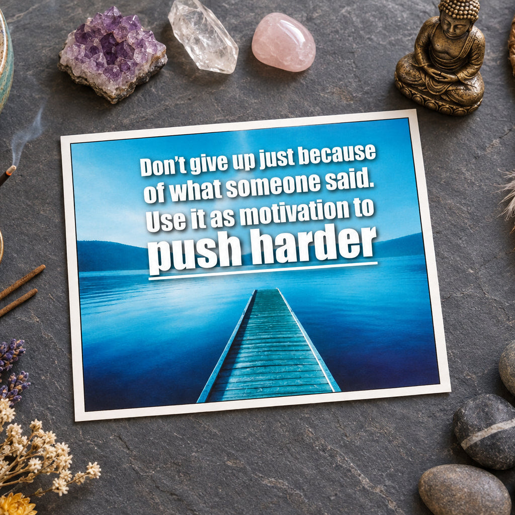 A motivational quote graphic with the text 'Don't give up just because of what someone said. Use it as motivation to push harder' in white over a scenic background of a wooden dock extending into calm blue water under a blue sky.