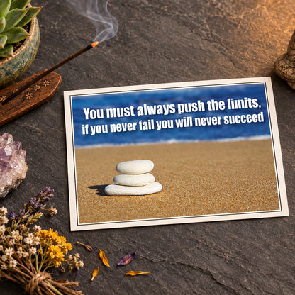 A motivational quote on a beach background: 'You must always push the limits, if you never fail you will never succeed' in white text over a blurred blue ocean and sandy shore. Three small white stones are stacked on the sand in the foreground.