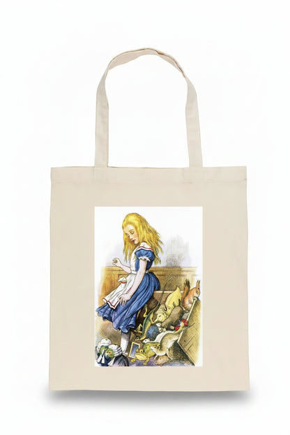 A natural canvas tote bag featuring a printed illustration of Alice in Wonderland with the Mad Hatter, rabbits, and a white rabbit on the front, set against a plain white background.