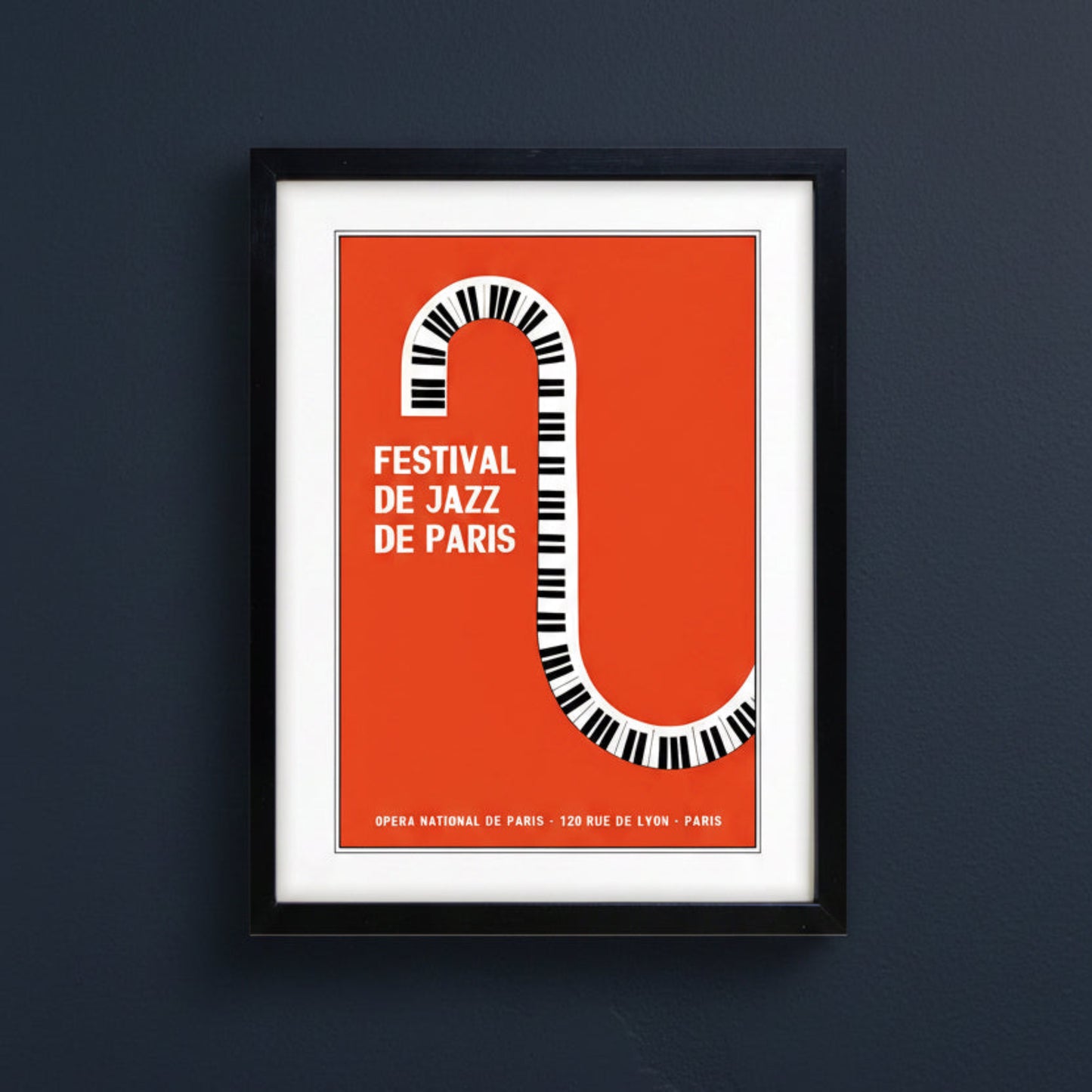 Framed poster print featuring a bold orange background with a stylized piano keyboard forming the letter S, alongside the text 'FESTIVAL DE JAZZ DE PARIS' in white. The print is matted in white and enclosed in a black frame, shown against a plain white background.
