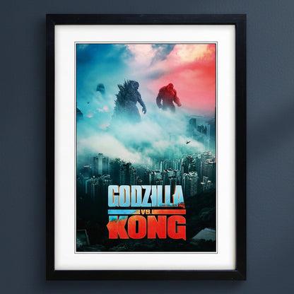 A framed Godzilla vs Kong movie poster featuring Godzilla and Kong in a cityscape with a dramatic blue-to-red sky, mounted against a dark gray wall.
