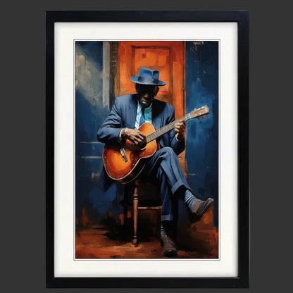 Framed wall art featuring a stylized painting of a man in a blue suit and hat playing an acoustic guitar, set against a vivid blue and orange background. The artwork is matted with a white border and enclosed in a black frame, shown on a plain white background. The painting is representative of Robert Johnson. The background is a dark slate grey wall.