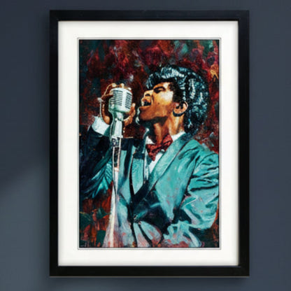 Framed canvas wall art featuring a colourful painted portrait of James Brown holding a vintage microphone, shown in a black frame with white matting against a light gray background. The frame is mounted on a dark blue wall with natural light filtering through.
