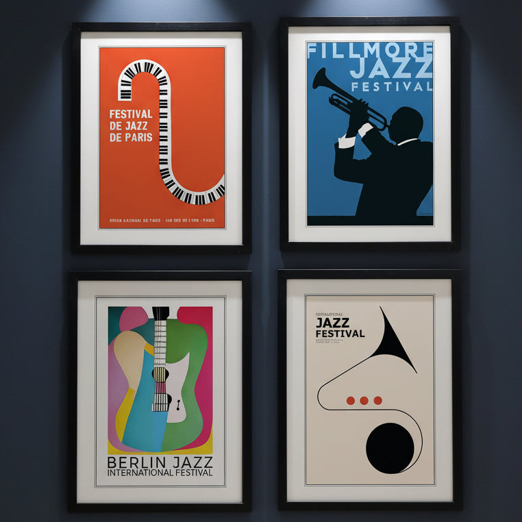 Four framed jazz festival art prints arranged in a 2x2 grid. The prints feature minimalist, retro-style illustrations: a red Paris Jazz Festival poster with a piano key curve, a blue Fillmore Jazz Festival poster with a trumpet player silhouette, a multicolor Berlin Jazz International Festival poster with a guitar, and a cream jazz poster with a saxophone shape.