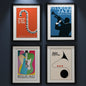 Four framed jazz festival art prints arranged in a 2x2 grid. The prints feature minimalist, retro-style illustrations: a red Paris Jazz Festival poster with a piano key curve, a blue Fillmore Jazz Festival poster with a trumpet player silhouette, a multicolor Berlin Jazz International Festival poster with a guitar, and a cream jazz poster with a saxophone shape.