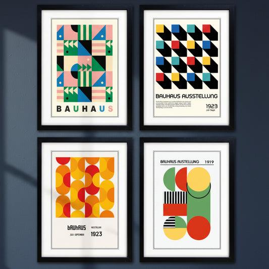 Four framed Bauhaus-style art prints arranged in a 2x2 grid. Each print features bold geometric shapes and typography, with black frames and white matting.