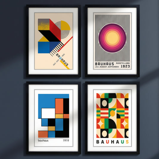 Four framed Bauhaus art prints arranged in a 2x2 grid on a white background. Each print features bold geometric shapes and typography in black, red, yellow, blue, green, and orange, with two prints showing the word 'BAUHAUS' and one showing 'bauhaus' in lowercase.