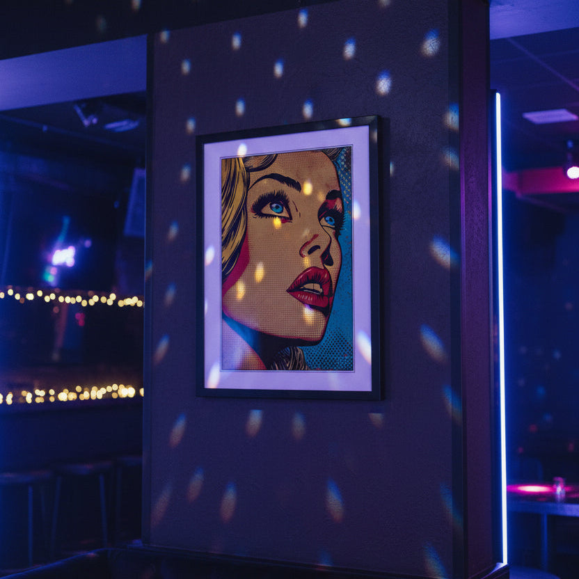 Framed pop art print featuring a stylized close-up portrait of a woman's face in bold yellow, orange, red, blue, and black halftone colors, shown against a plain white background.