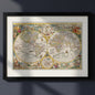 A framed vintage world map print with an ornate black frame and white mat, displayed against a dark gray wall with soft diagonal shadows.