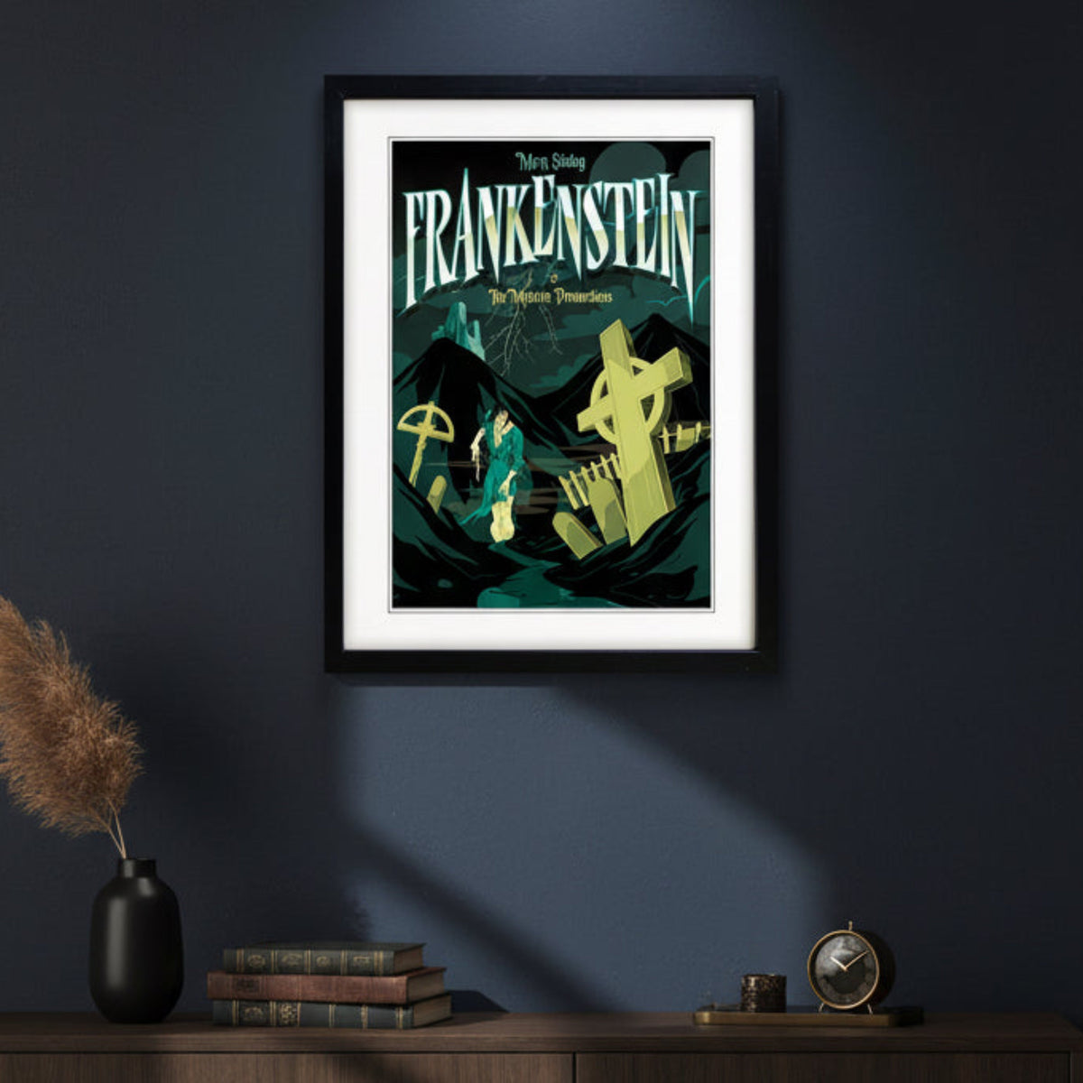 A framed gothic movie poster for 'Frankenstein: The Modern Prometheus' starring Mary Shelley, featuring a stylized illustration of a figure in a green coat in a graveyard with tombstones under a dark teal sky, presented in a black frame with a white mat.