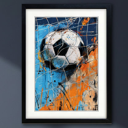 Framed wall art featuring a stylized soccer ball in a dynamic abstract painting with blue, orange, black, and white paint splatters, set against a dark gray wall.