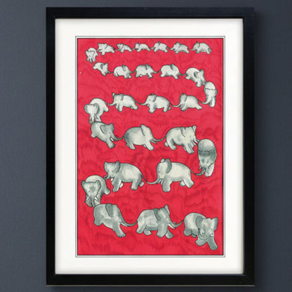 A framed art print featuring a red background with a series of gray baby elephants in various poses, bordered by a white mat and a black frame, shown against a dark gray wall.