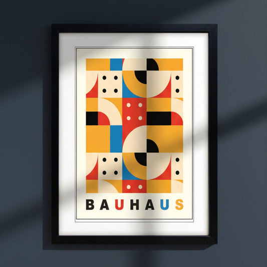 A framed Bauhaus art print featuring a colorful geometric abstract design with the word 'BAUHAUS' at the bottom, enclosed in a black frame against a white background.