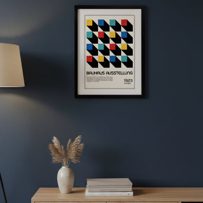 A framed Bauhaus exhibition poster print featuring a geometric pattern of black diagonal blocks with colored squares in yellow, red, blue, and teal on an off-white background, enclosed in a black frame with a white mat.