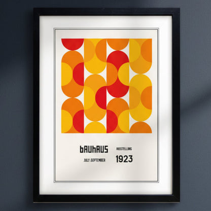 A framed Bauhaus poster featuring a bold mid-century geometric pattern in orange, yellow, and red, with the text 'BAUHAUS RUSSELLING JULY-SEPTEMBER 1923' below, shown in a black frame against a white background.