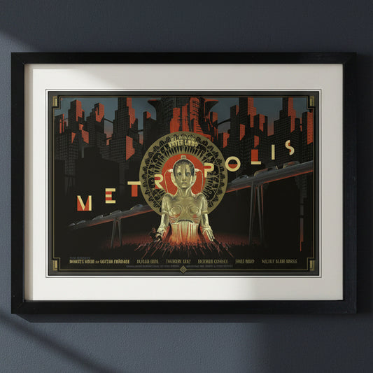A framed art print featuring a stylized Metro-polis cityscape poster design with a central robot figure, shown in a black frame with a white mat against a light gray background.