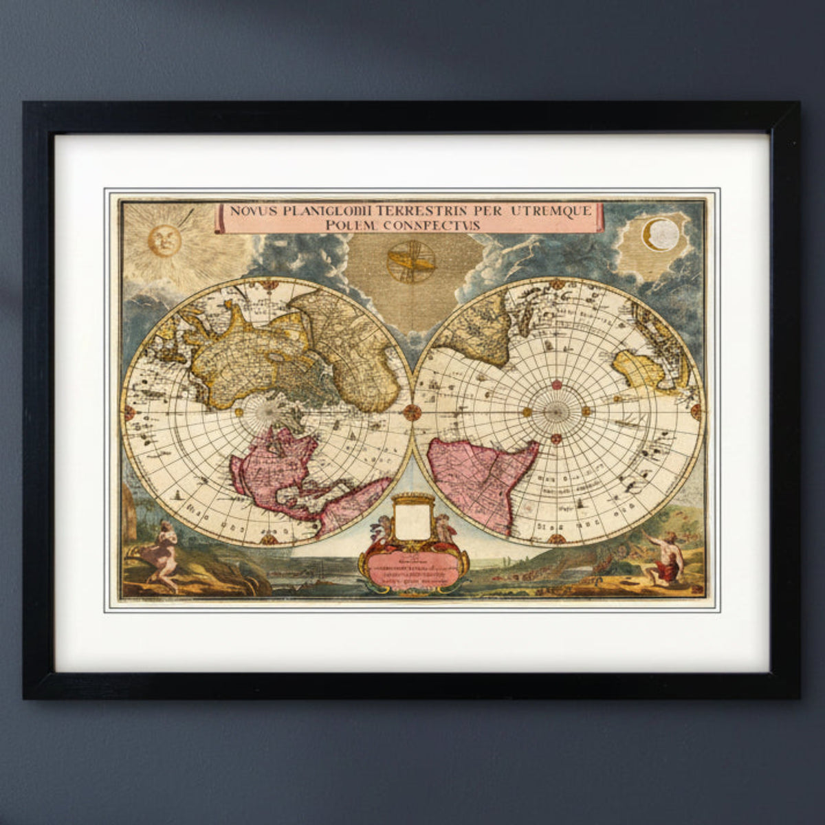 Antique reproduction world atlas map in black frame with white mount on a blu wall with natural lighting 