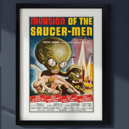 A framed vintage-style sci-fi movie poster titled 'Invasion of the Saucer-Men' with a black frame and white mat, shown against a plain dark blue  wall background.