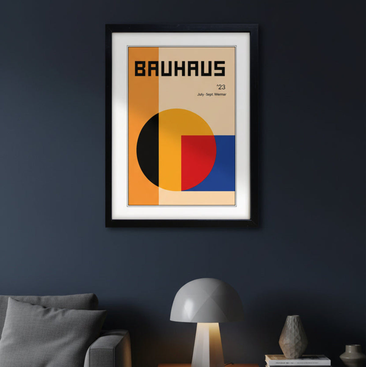 A framed Bauhaus '23 art print featuring a minimalist geometric design with orange, beige, yellow, red, and blue blocks, presented in a modern apartment with minimalistic furniture.
