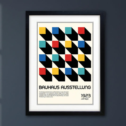 A framed Bauhaus exhibition poster print featuring a geometric pattern of black diagonal blocks with colored squares in yellow, red, blue, and teal on an off-white background, enclosed in a black frame with a white mat.