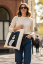 A cream-colored canvas tote bag featuring a graphic print of a stylized black and white dog portrait on a dark blue background, with the text 'OHRADIUS-STUDIE: SPINNEL PORTRAIT' at the top.