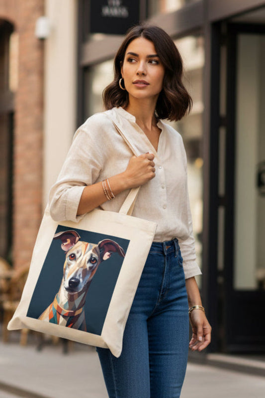 A woman wearing a cream linen shirt and blue jeans carries a canvas tote bag with a custom printed portrait of a greyhound dog on a dark background, set against a blurred city street backdrop.