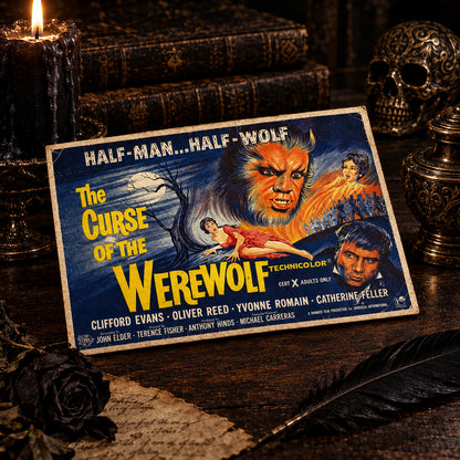 A vintage Technicolor movie poster for 'The Curse of the Werewolf' resting on a dark wooden tabletop. The poster features illustrated artwork of a werewolf face, a woman in a red dress, and other characters, with the title in large yellow letters.