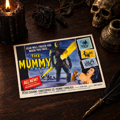 A vintage movie poster for 'The Mummy' lies flat on a dark wooden tabletop. The poster features illustrated artwork of a mummy holding a glowing yellow sword, with a woman in the lower right corner and bold yellow title text.