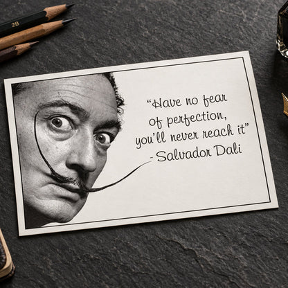 Black and white portrait of Salvador Dalí with his signature curled mustache, next to a handwritten quote that reads: 'Have no fear of perfection, you'll never reach it' - Salvador Dalí.