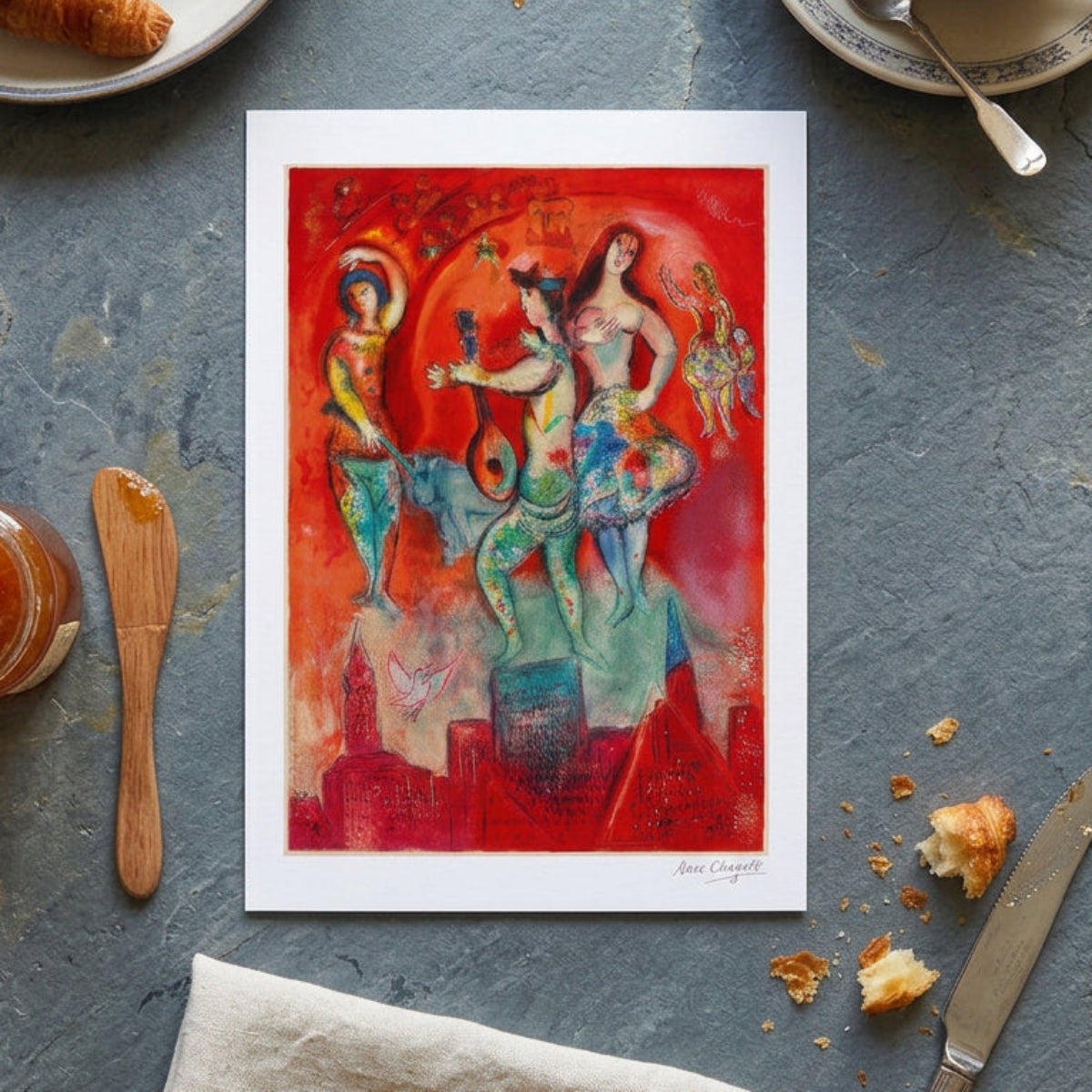 A colorful framed painting on a gray gradient background. The artwork depicts stylized dancing figures, a lute-like instrument, small cherubs, and a cityscape in vivid red, orange, teal, yellow, and blue tones.