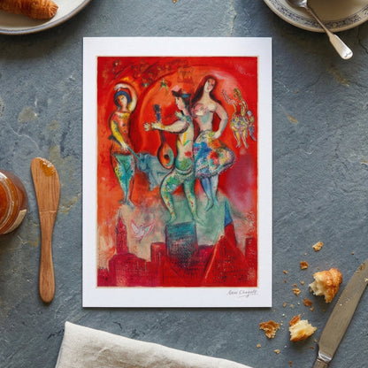 A colorful framed painting on a gray gradient background. The artwork depicts stylized dancing figures, a lute-like instrument, small cherubs, and a cityscape in vivid red, orange, teal, yellow, and blue tones.