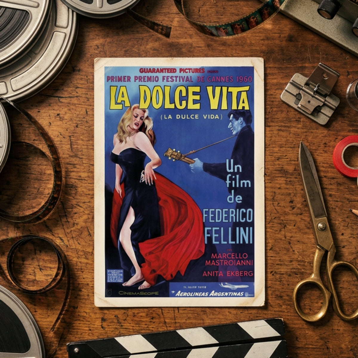 A framed vintage movie poster for Federico Fellini's 'La Dolce Vita' (1960), featuring a blonde woman in a black dress with a flowing red skirt against a blue background, with a dark figure holding a guitar. The poster is displayed on a neutral gray gradient background.