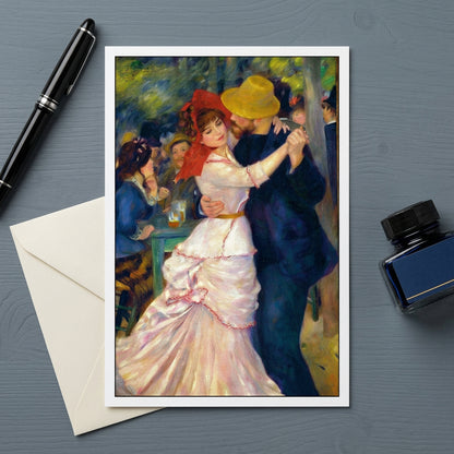 A framed art print of renoir Impressionist painting 'Dancers' is displayed on a dark gray slate background, styled with vintage beige envelopes and a wooden pen in a tray.