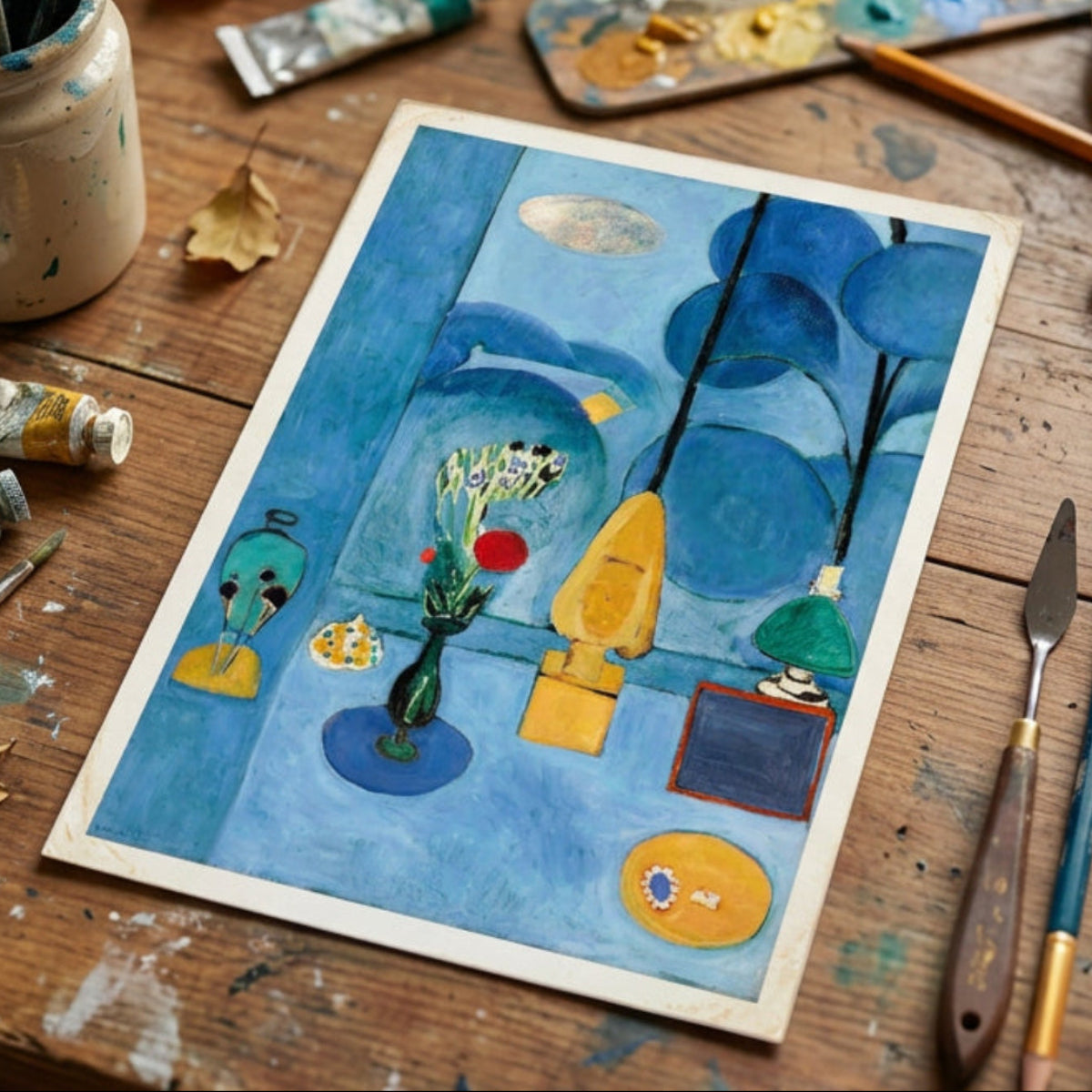 An abstract still life painting featuring blue tones with yellow, green, red, and black elements, including a vase with flowers, hanging forms, and geometric shapes, shown against a neutral gray gradient background.