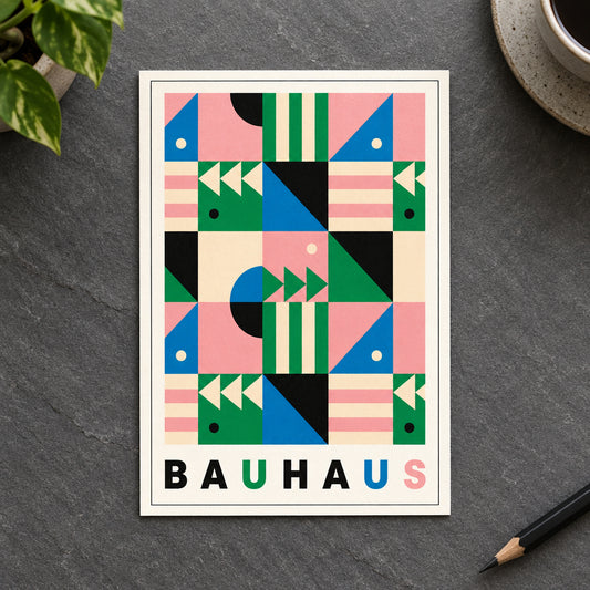 A framed Bauhaus-style geometric art print featuring a colorful abstract pattern with pink, green, blue, black, and cream shapes, with the word 'BAUHAUS' printed at the bottom, shown against a gray gradient background.