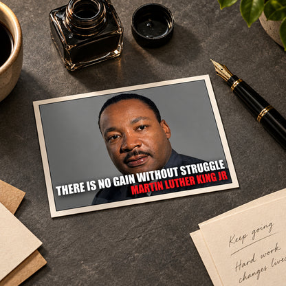 A framed print or poster featuring a portrait of Martin Luther King Jr. with the quote 'THERE IS NO GAIN WITHOUT STRUGGLE' in white text and 'MARTIN LUTHER KING JR' in red text, shown against a gray gradient background.