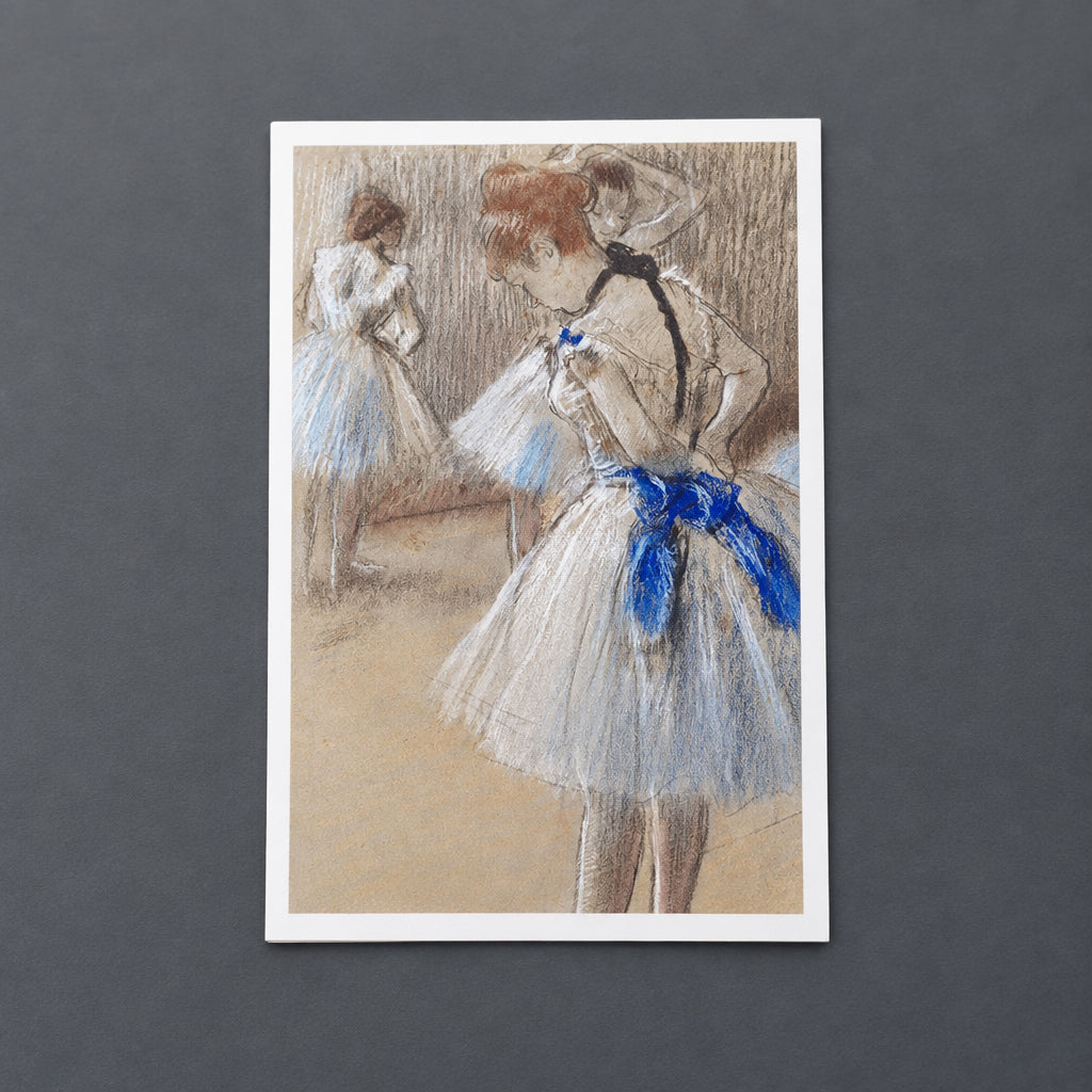 A pastel drawing of ballet dancers in tutus, with the central figure in a white tutu and bright blue sash, another dancer in a blue-and-white tutu facing away, and a softly blurred background.