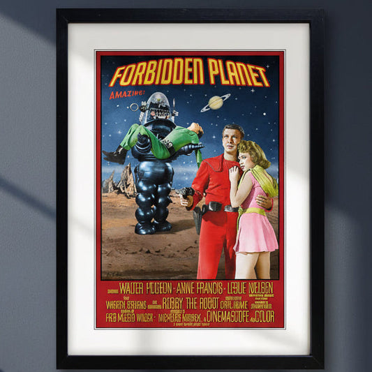 A framed vintage movie poster for 'Forbidden Planet' with a black frame and white mat, showing a retro sci-fi scene with a robot, a man in red, and a woman in pink against a starry space background.