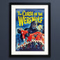 Framed vintage-style poster art for 'The Curse of the Werewolf' with a black frame, white mat, and a dramatic illustration showing a werewolf holding a woman in a red dress against a blue night sky.