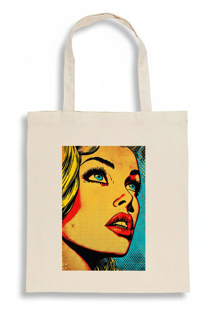 A cream-colored canvas tote bag featuring a colorful pop-art graphic of a woman's face on the front, set against a plain white background.