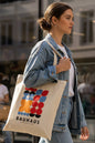 A cream-colored canvas tote bag featuring a colorful Bauhaus geometric logo print in red, orange, blue, black, and white, with the text 'BAUHAUS INSTITUTE OF ART AND DESIGN' printed below.